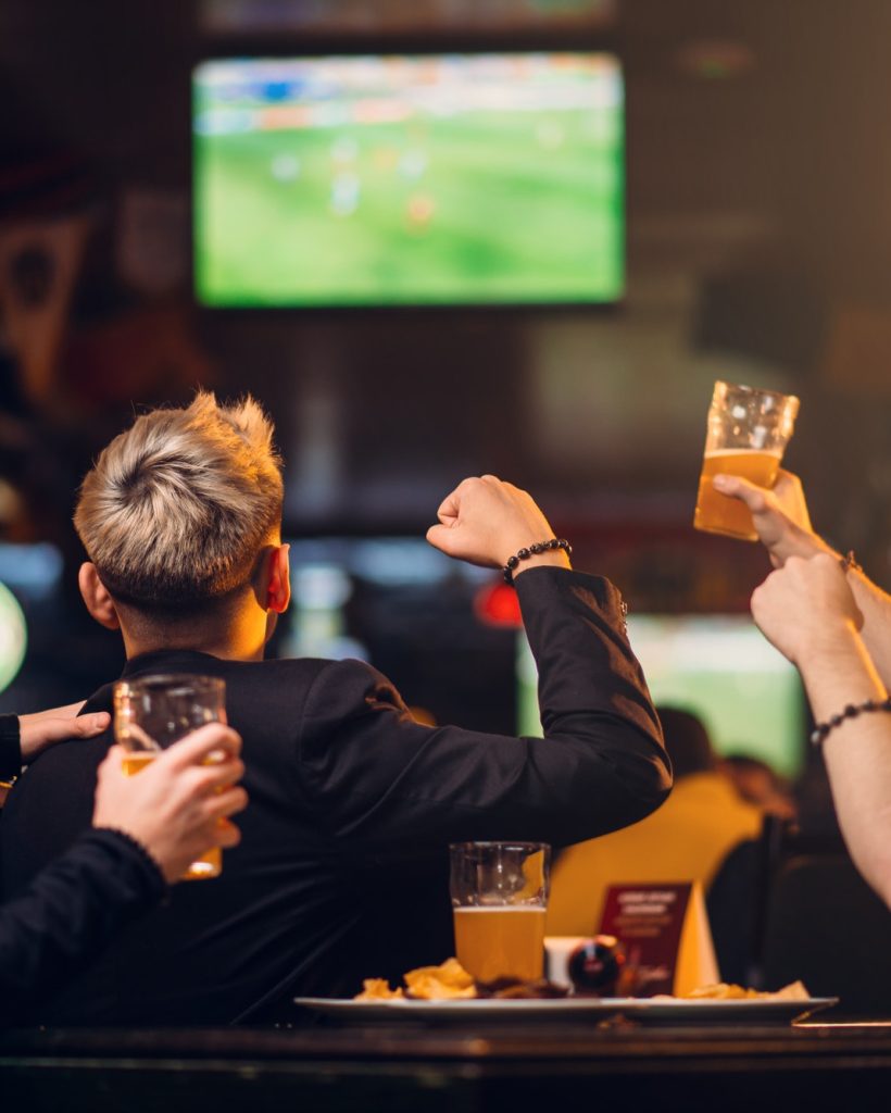 Three men watch football on TV in a sports bar